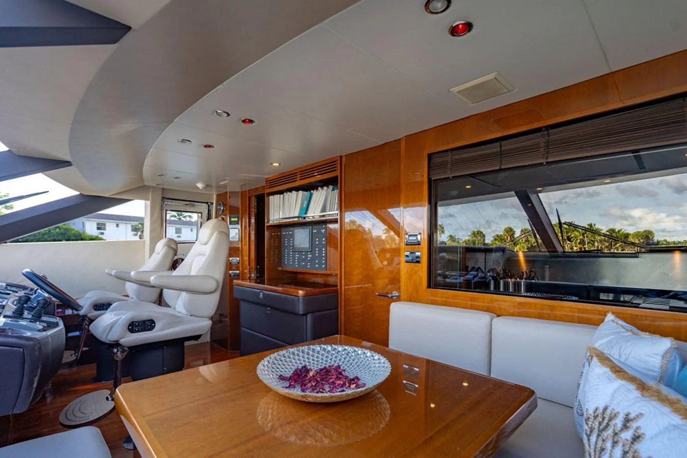 The helm area features luxurious seating and a well-appointed control panel, complemented by a cozy dining nook. aboard OASIS Yacht for Sale
