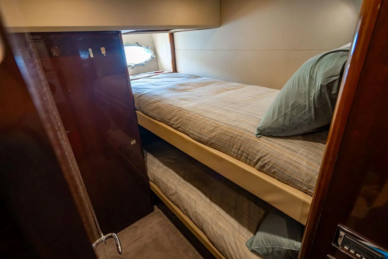 The cozy guest cabin features bunk beds and a small porthole for natural light. aboard OASIS Yacht for Sale