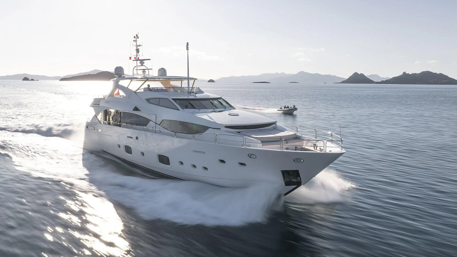 A sleek and modern yacht cruises swiftly through calm waters with a stunning backdrop of islands. aboard FINAL CUT Yacht for Sale