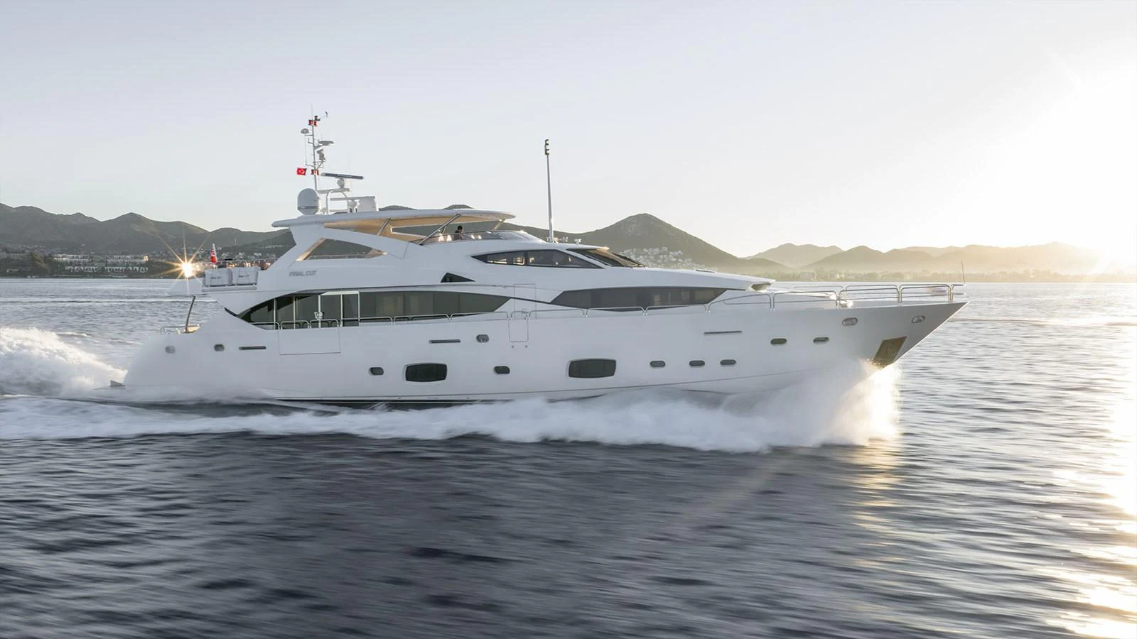 A sleek and modern yacht cruises gracefully on calm waters at sunset. aboard FINAL CUT Yacht for Sale