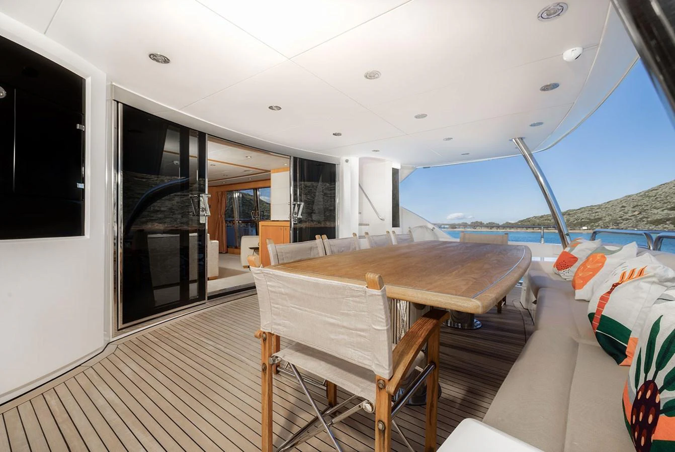 The aft deck features a spacious dining area with a large wooden table and comfortable seating, perfect for alfresco dining. aboard FINAL CUT Yacht for Sale