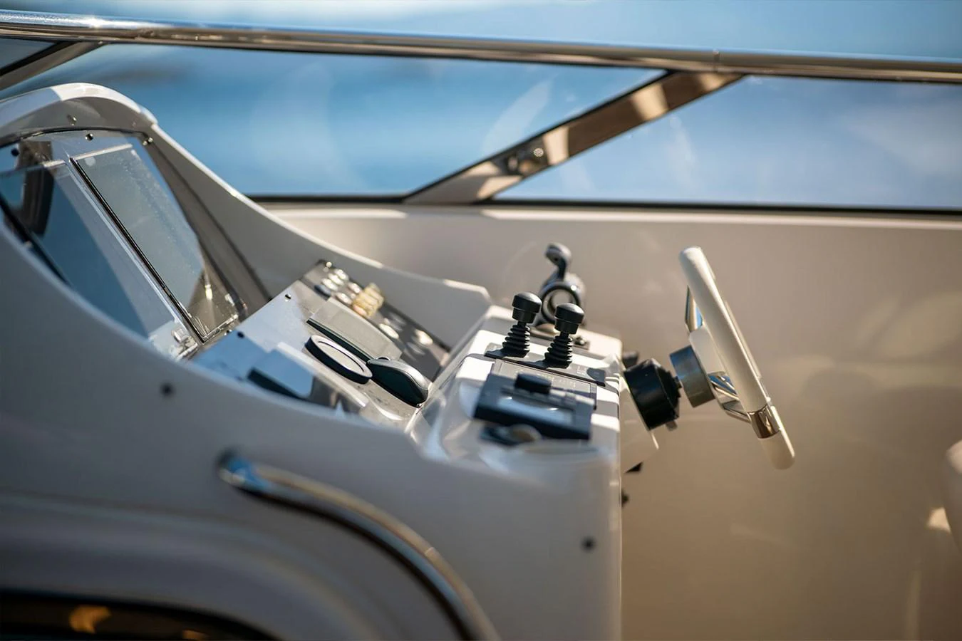 The helm station features modern controls and a sleek steering wheel, set against a backdrop of clear skies and water. aboard FINAL CUT Yacht for Sale