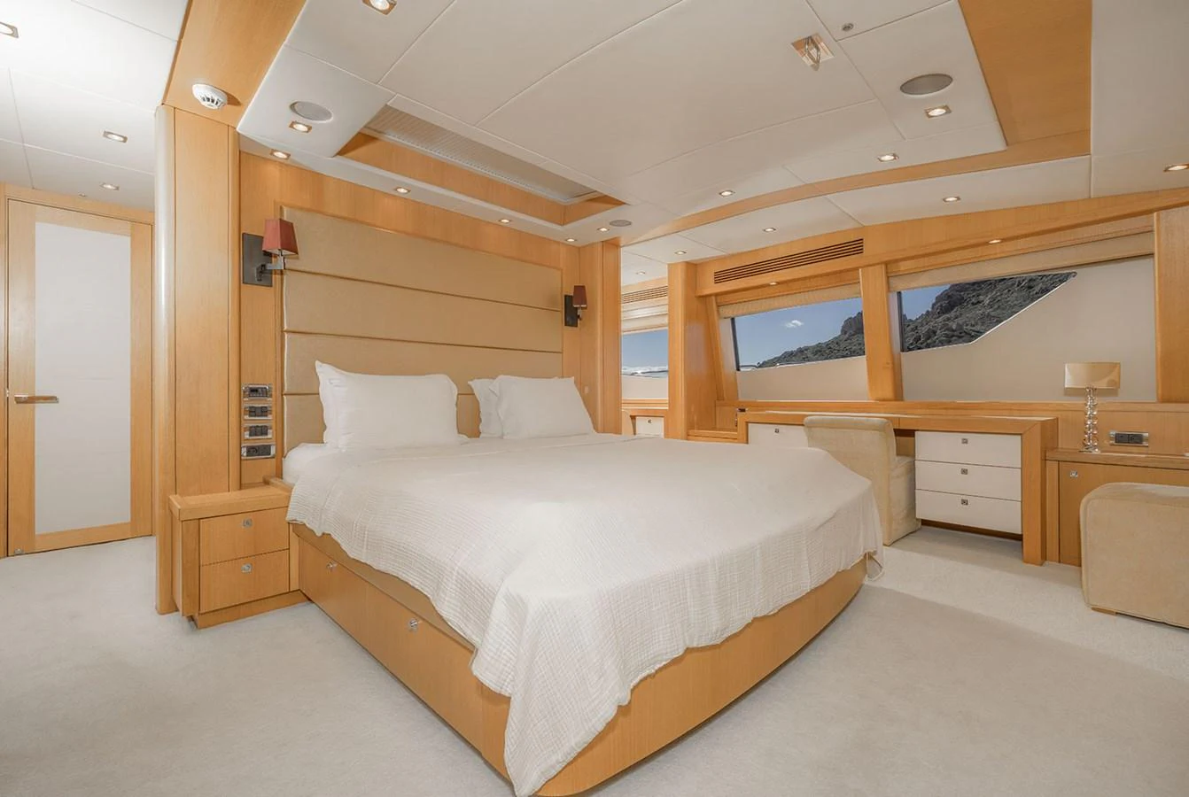 The master stateroom features a spacious bed, elegant wood finishes, and large windows offering scenic views. aboard FINAL CUT Yacht for Sale