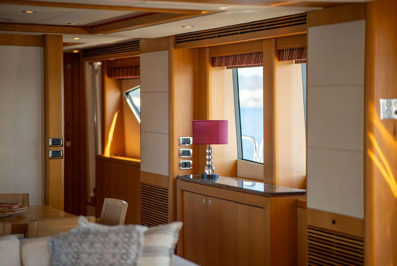 The yacht's interior features a cozy and elegant living space with warm wood finishes and a stylish lamp. aboard FINAL CUT Yacht for Sale