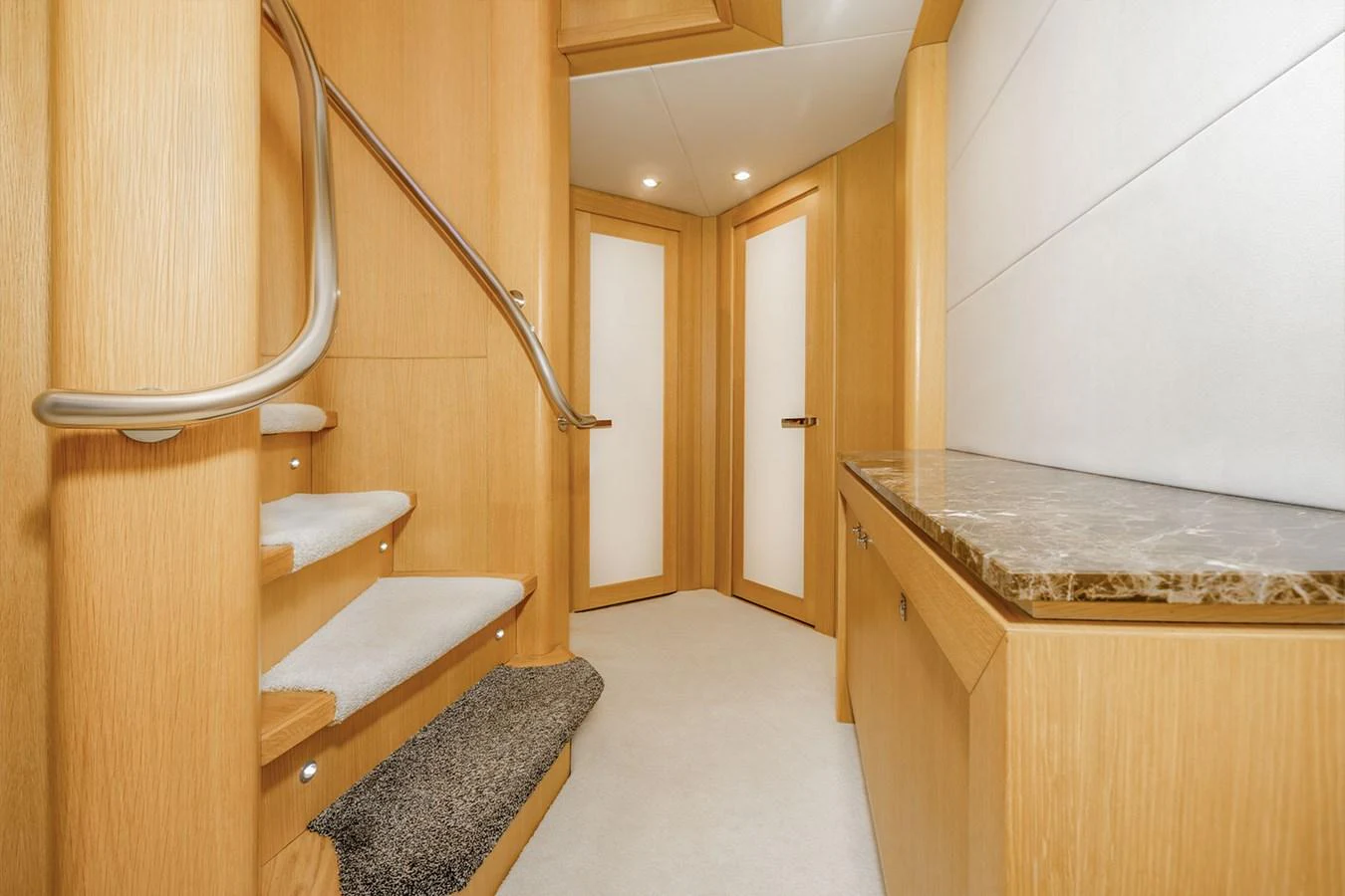 A well-lit interior hallway with wooden finishes and a staircase leading to another level. aboard FINAL CUT Yacht for Sale
