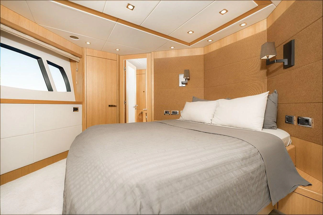 The stateroom features a comfortable bed with modern lighting and ample natural light from the windows. aboard FINAL CUT Yacht for Sale