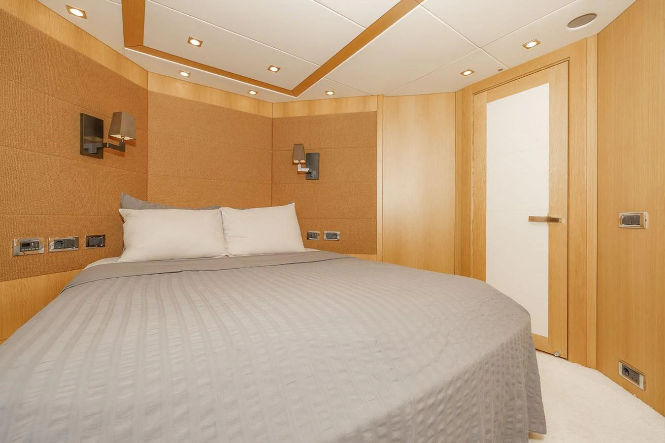 The stateroom features a cozy bed with modern lighting and wood paneling. aboard FINAL CUT Yacht for Sale