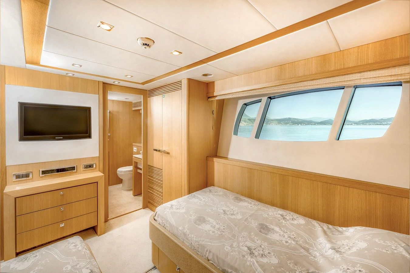 A luxurious stateroom featuring a large bed, ample storage, and a view of the sea through wide windows. aboard FINAL CUT Yacht for Sale