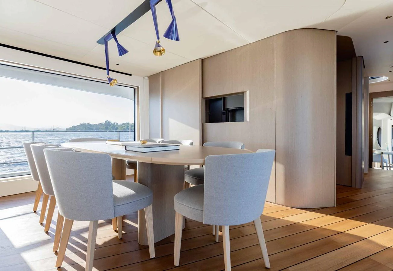 The yacht's dining area features a modern table with plush seating and large windows offering stunning views. aboard MARYBELLE Yacht for Sale