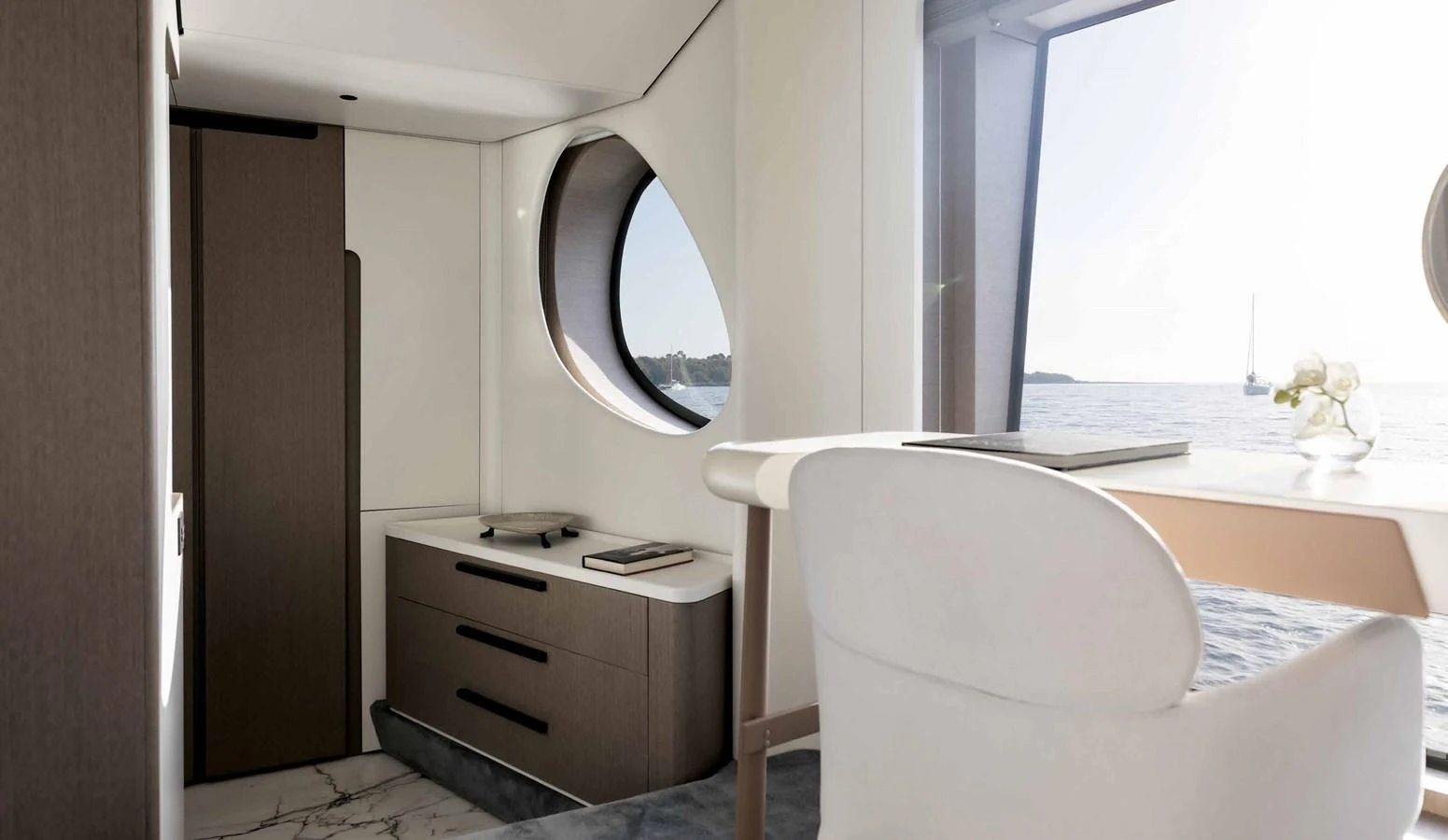 A serene and modern interior space with a large circular window offering a view of the sea. aboard MARYBELLE Yacht for Sale