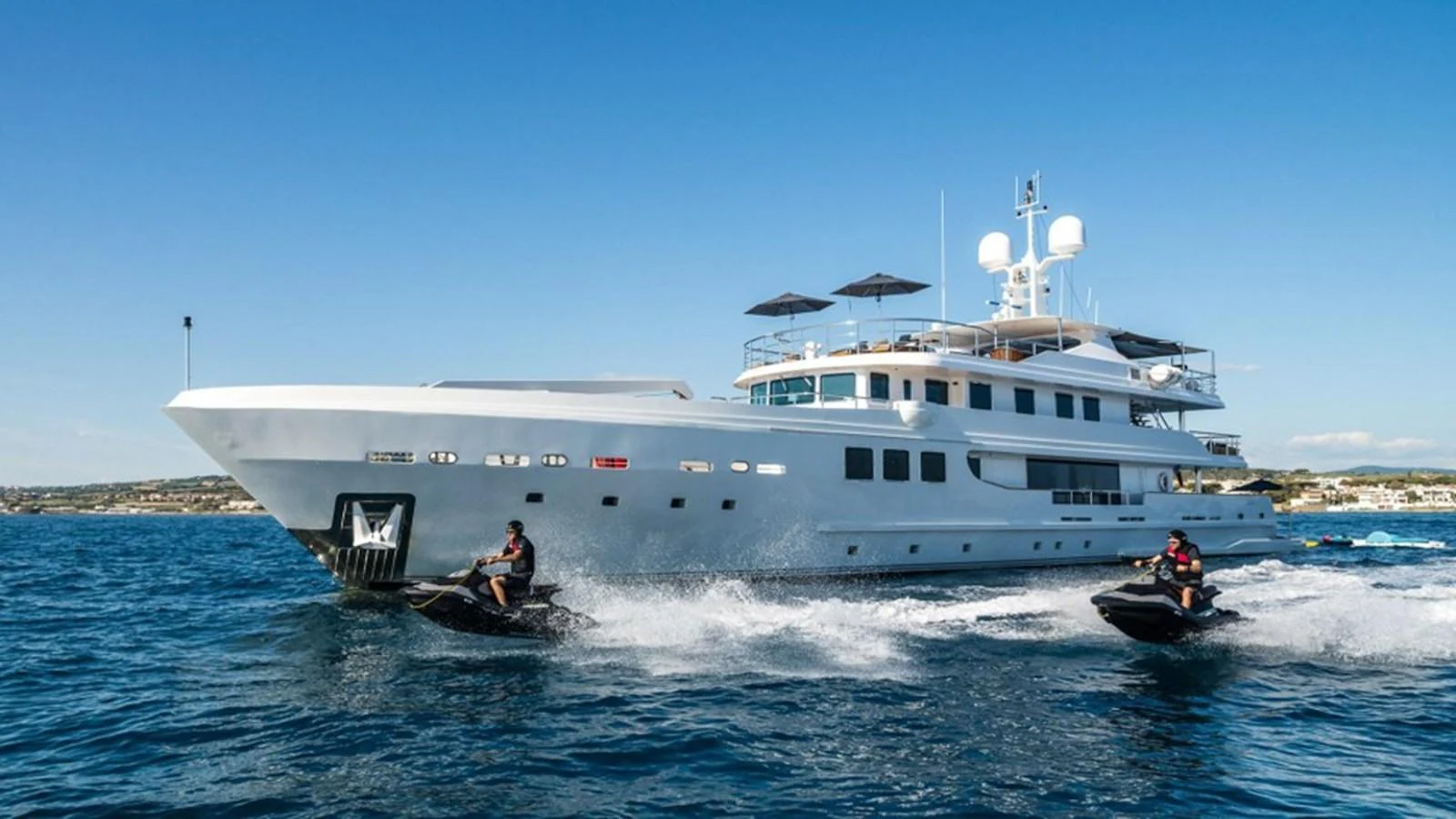 A luxurious yacht cruises through the water accompanied by two jet skis. aboard R23 Yacht for Sale