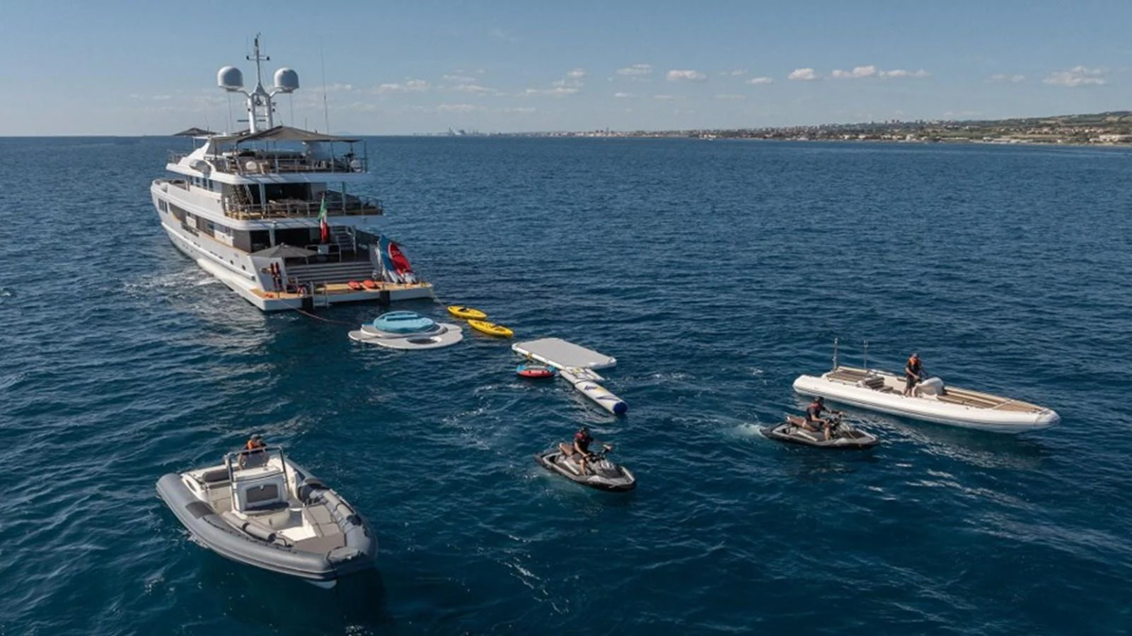 The yacht is anchored in serene blue waters, surrounded by various water toys and tenders, offering a perfect blend of luxury and adventure. aboard R23 Yacht for Sale