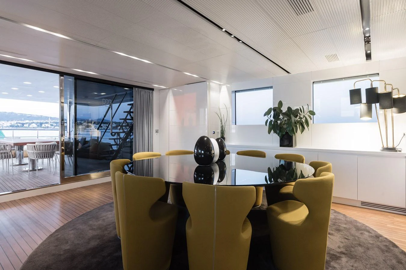 The yacht's dining area features a sleek, modern design with a large round table and comfortable seating. aboard R23 Yacht for Sale