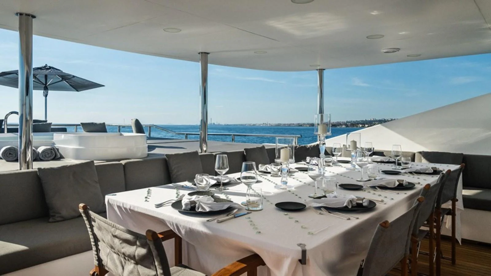 An elegant alfresco dining area set for a meal, offering stunning ocean views. aboard R23 Yacht for Sale