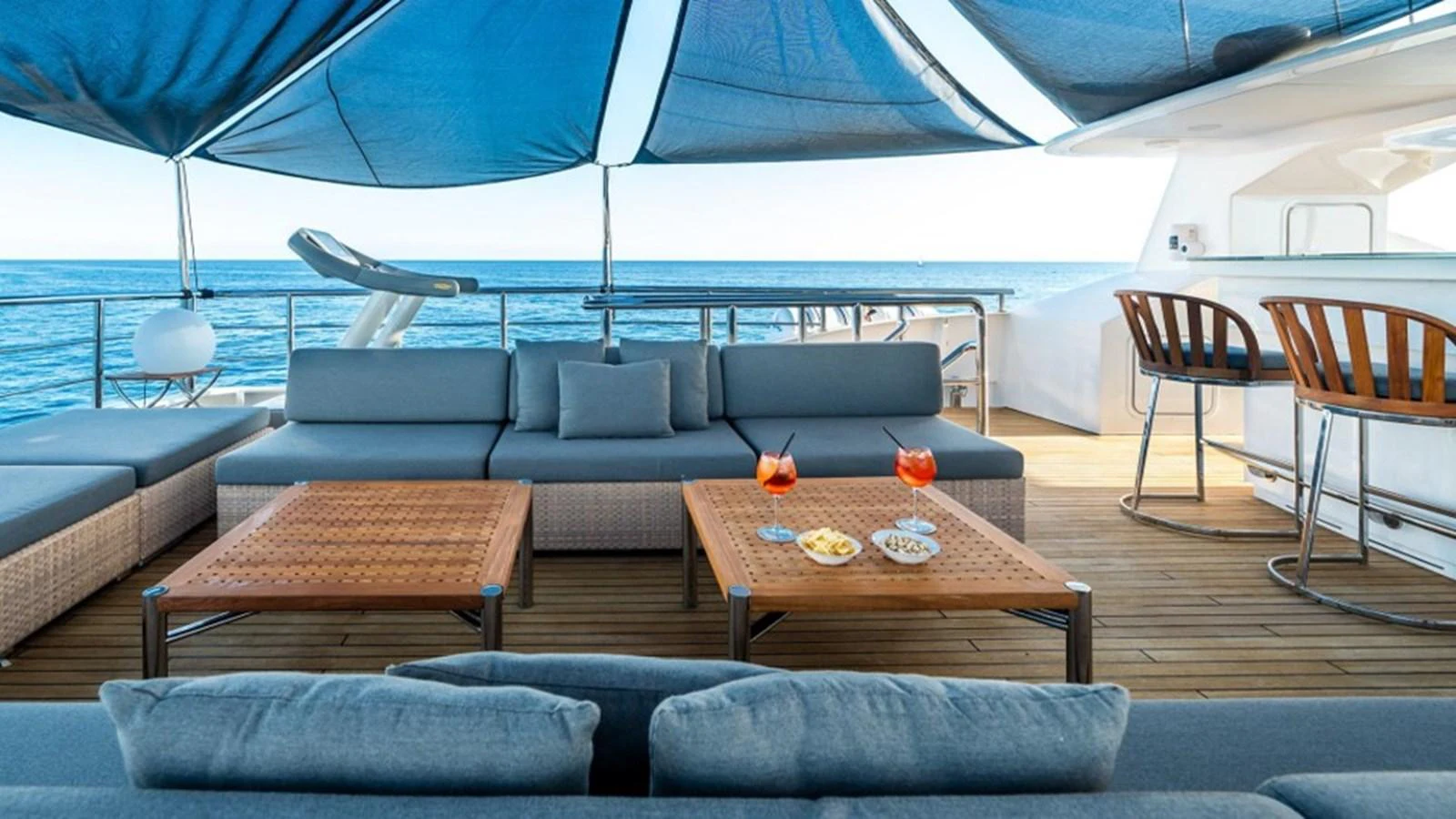 The aft deck features a comfortable lounge area with a bar, perfect for relaxing and enjoying the ocean view. aboard R23 Yacht for Sale