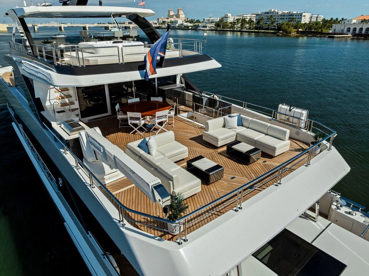 The yacht's aft deck features a spacious lounging area with plush seating and a dining table, perfect for outdoor relaxation and entertainment. aboard SERENITY NOW Yacht for Sale