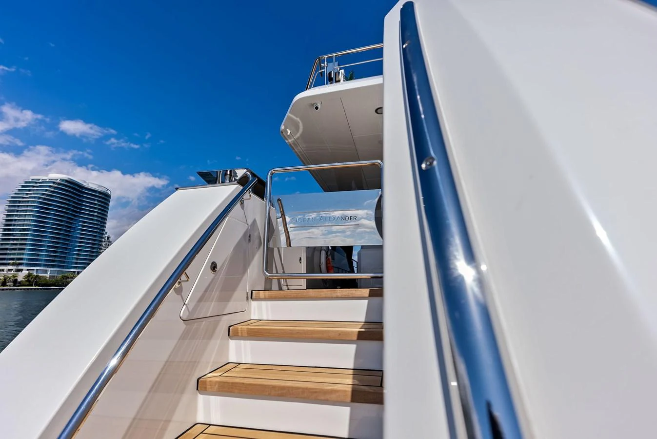 A sleek staircase with wooden steps and stainless steel railings leads to the upper deck of the yacht. aboard SERENITY NOW Yacht for Sale