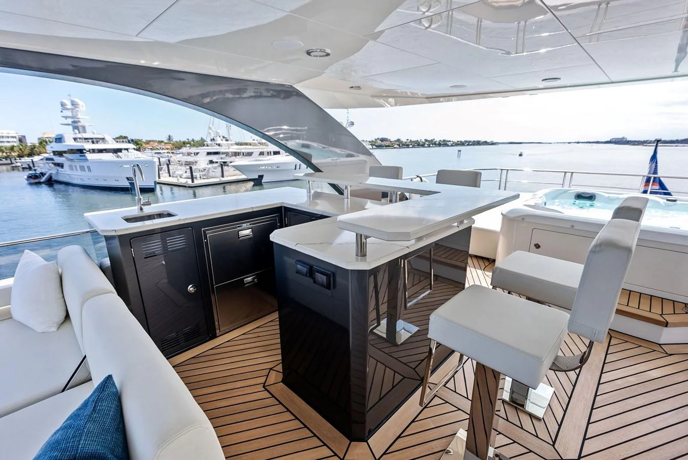 The flybridge features a sleek bar area with high stools and a view of the surrounding marina. aboard SERENITY NOW Yacht for Sale