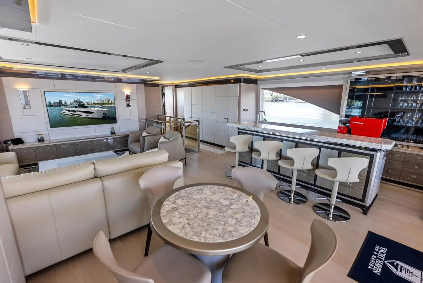 The yacht's salon features a luxurious seating area, a bar with stools, and a large TV screen. aboard SERENITY NOW Yacht for Sale