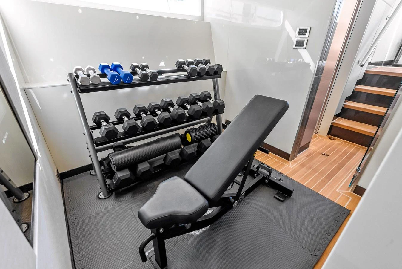 The yacht features a well-equipped gym with a variety of weights and a bench for workouts. aboard SERENITY NOW Yacht for Sale