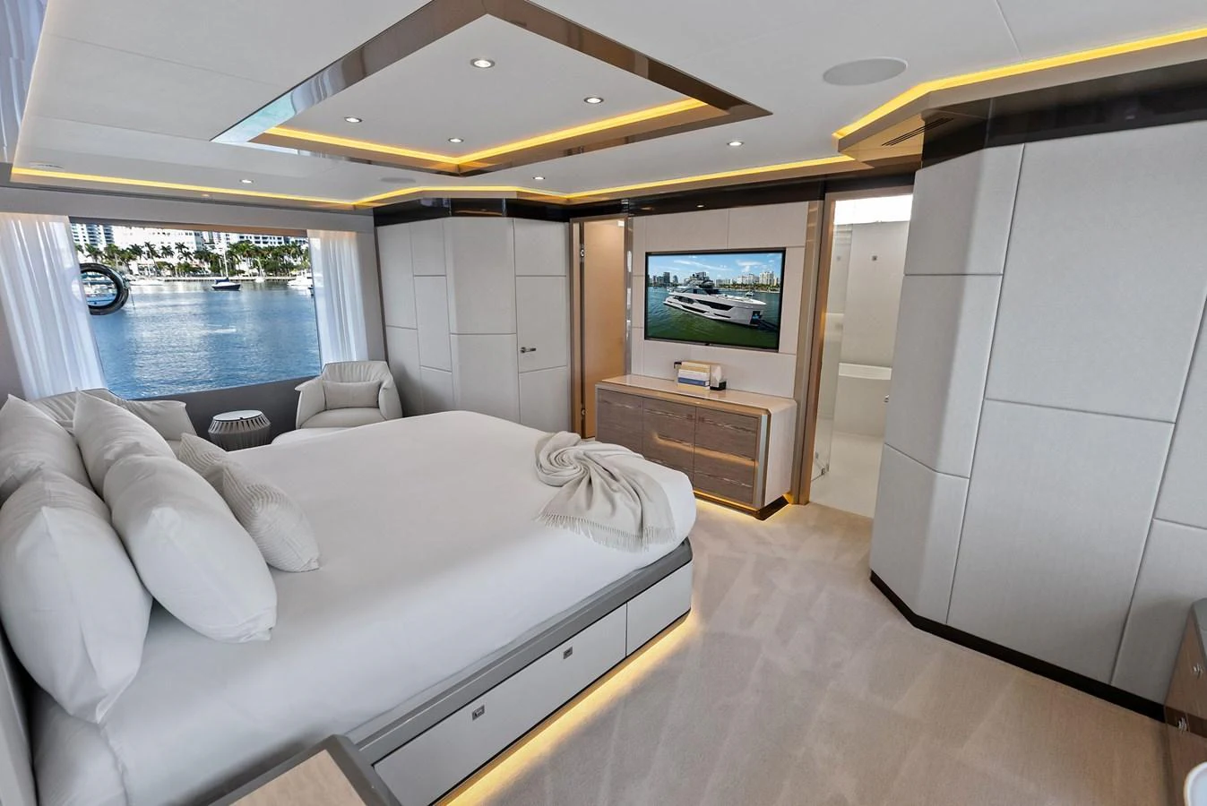 The master stateroom features a luxurious bed, ample storage, and a large window with a scenic view. aboard SERENITY NOW Yacht for Sale