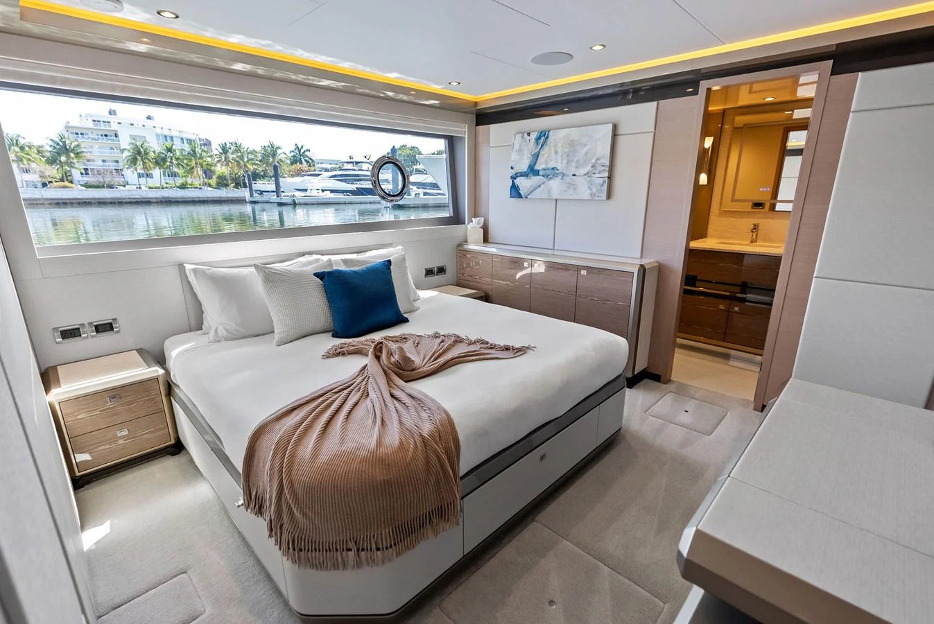 A luxurious stateroom featuring a large bed with elegant decor and a view of the marina through a wide window. aboard SERENITY NOW Yacht for Sale