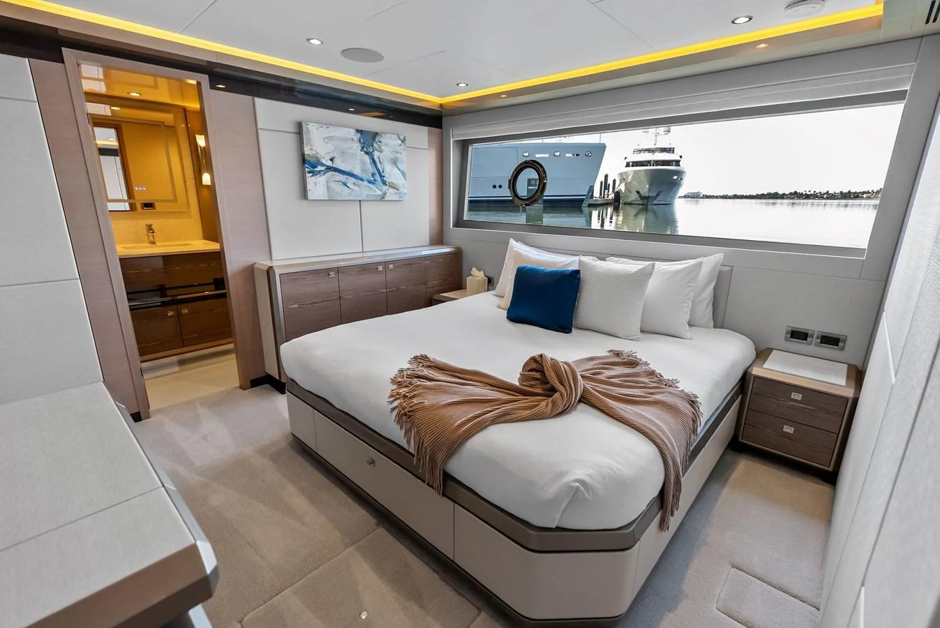 The stateroom features a luxurious bed with a view of the sea through a large window. aboard SERENITY NOW Yacht for Sale