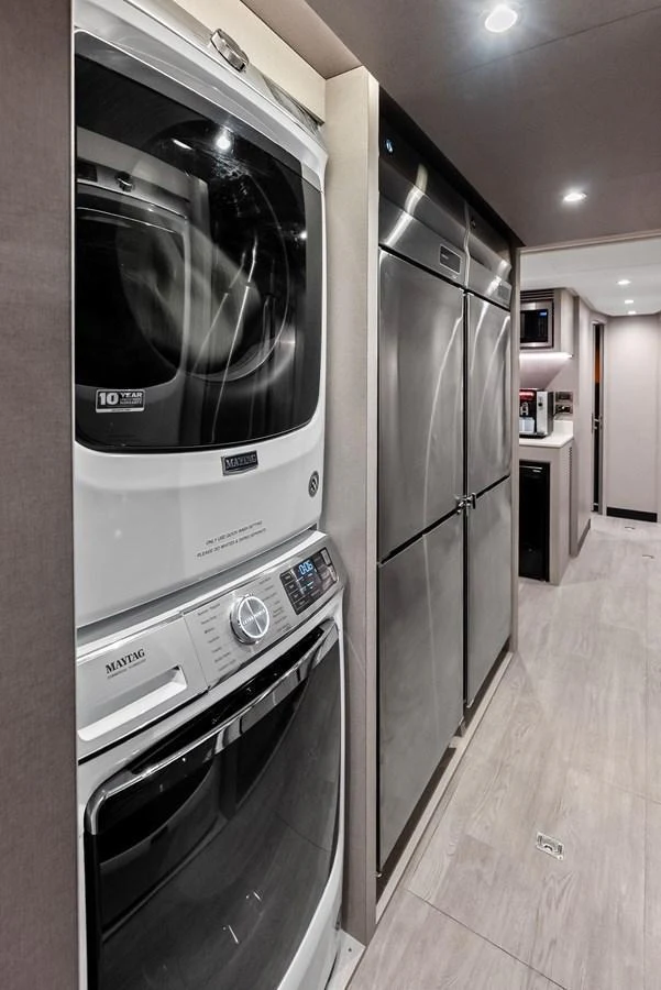 The yacht's interior features a modern laundry area with stacked appliances and ample storage space. aboard SERENITY NOW Yacht for Sale