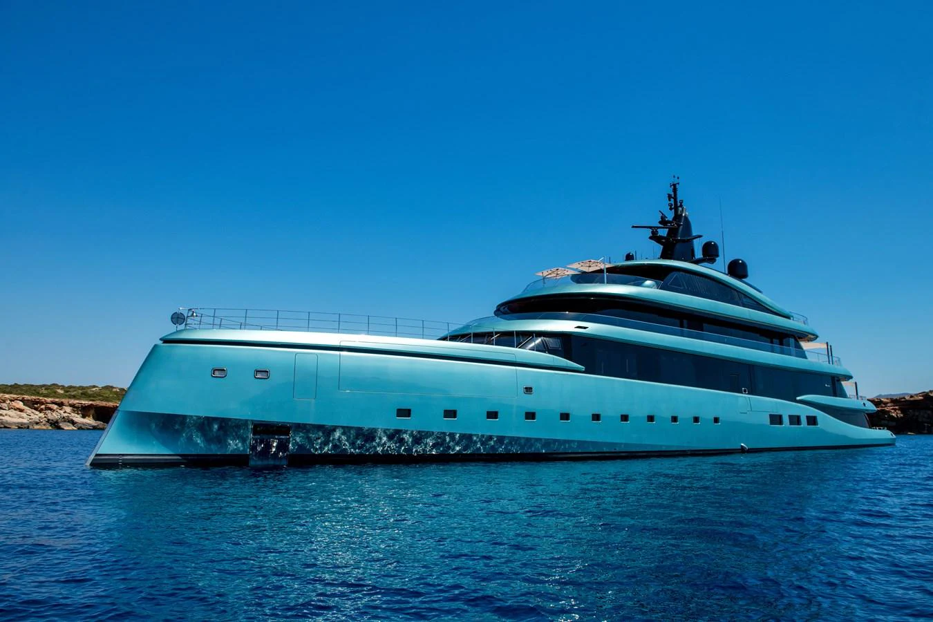 A sleek and modern yacht glides gracefully on the clear blue waters under a bright sky. aboard KENSHO Yacht for Sale