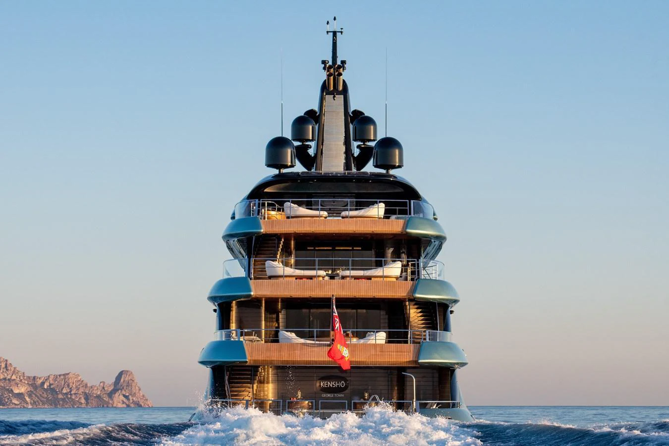 A luxurious yacht sails away, showcasing its impressive multi-deck structure against a serene seascape. aboard KENSHO Yacht for Sale