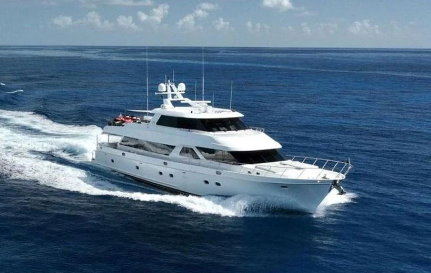 A sleek white yacht cruises through the open ocean under a clear blue sky. aboard ROBIN'S NEST Yacht for Sale