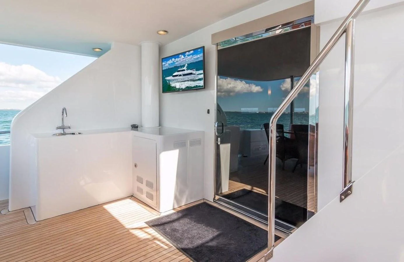 The aft deck features a sleek design with a TV and a small kitchenette area. aboard ROBIN'S NEST Yacht for Sale
