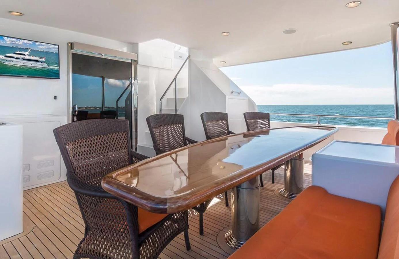 The aft deck features a polished wooden dining table with wicker chairs, offering a perfect spot for alfresco dining with a view of the sea. aboard ROBIN'S NEST Yacht for Sale