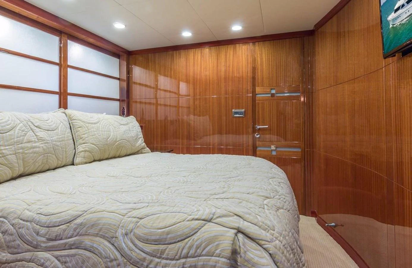 The stateroom features a comfortable bed with elegant wood paneling and modern lighting. aboard ROBIN'S NEST Yacht for Sale