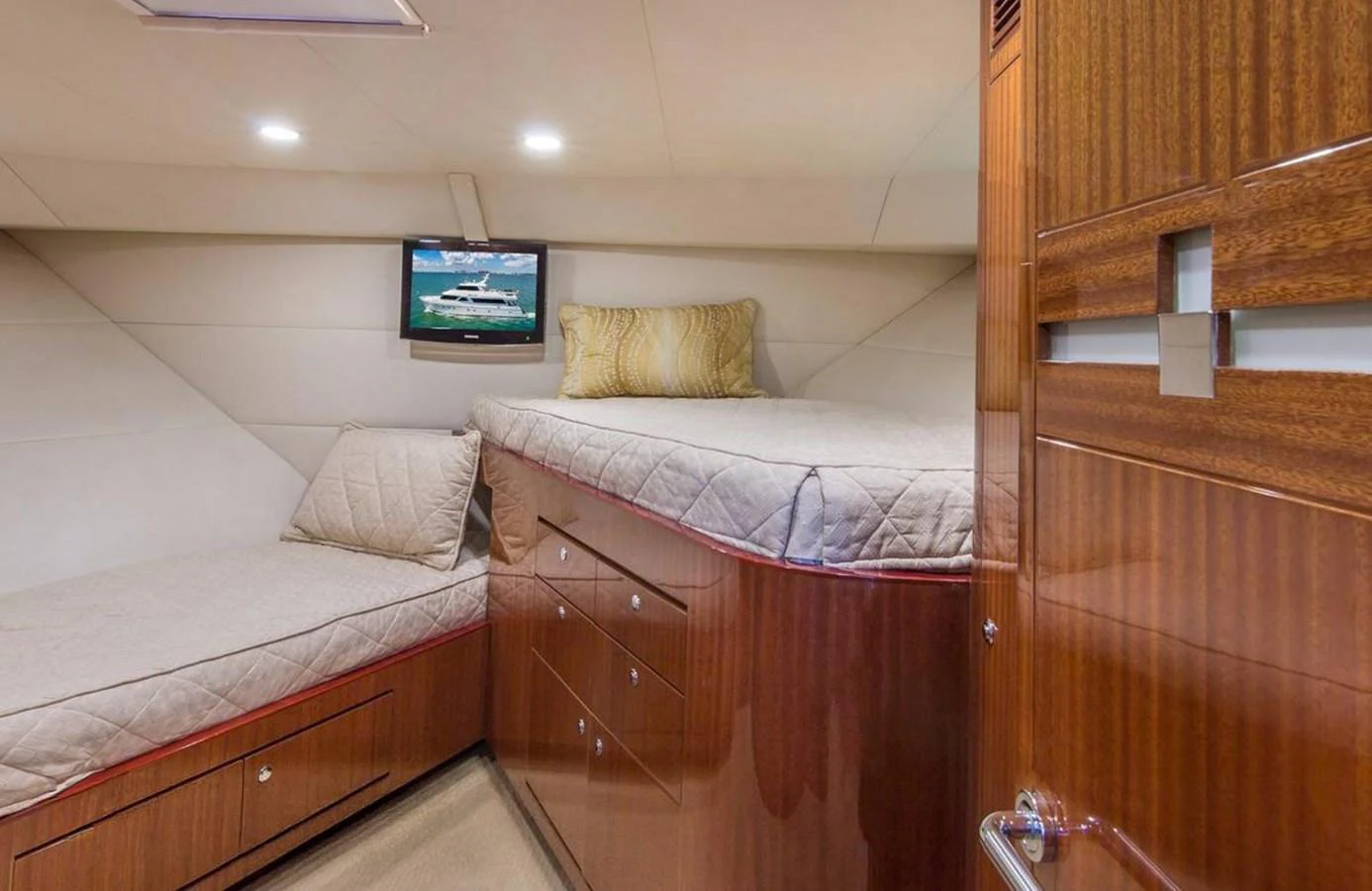 The guest cabin features twin beds with a wall-mounted TV and elegant wooden cabinetry. aboard ROBIN'S NEST Yacht for Sale
