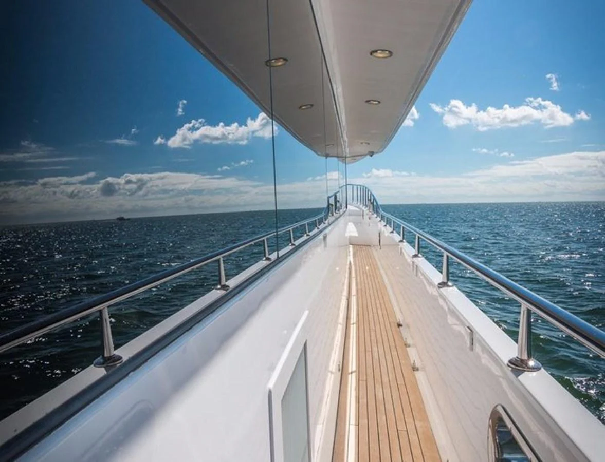 A sleek side deck with polished railings and a wooden walkway, set against a serene ocean backdrop. aboard ROBIN'S NEST Yacht for Sale