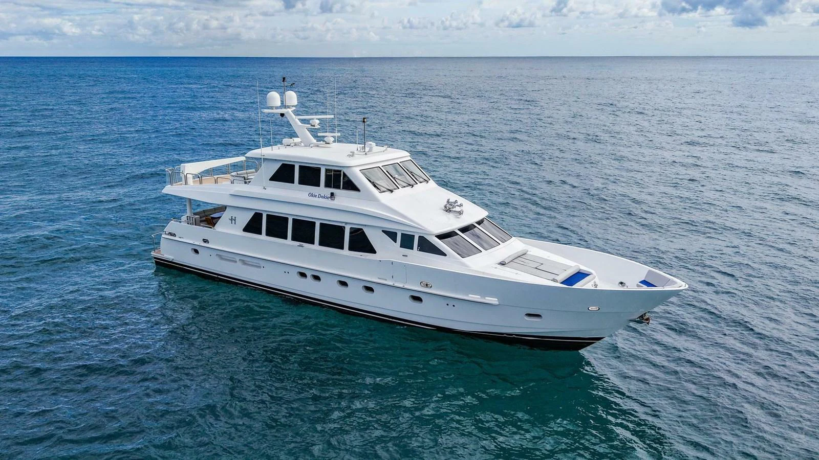 A sleek white yacht cruises gracefully on the open sea under a partly cloudy sky. aboard BOBBI TOO Yacht for Sale