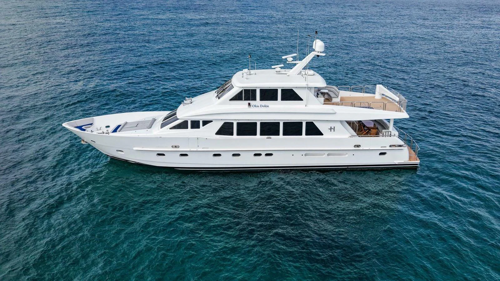 A sleek white yacht glides gracefully on calm blue waters, showcasing its elegant design and spacious decks. aboard BOBBI TOO Yacht for Sale