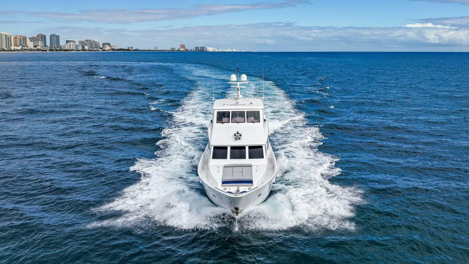 A sleek yacht cruises through the open ocean, leaving a trail of white wake behind. aboard BOBBI TOO Yacht for Sale