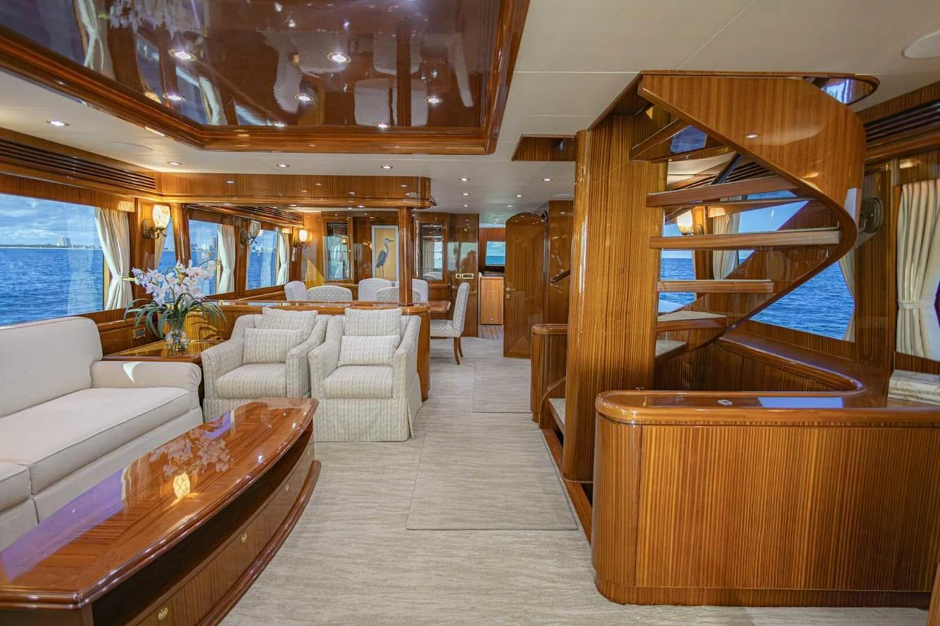 The yacht's salon features luxurious seating, elegant wood finishes, and large windows offering stunning ocean views. aboard BOBBI TOO Yacht for Sale