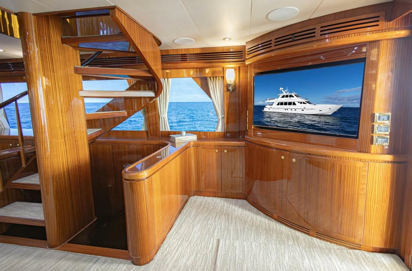 The yacht's interior features elegant wood paneling and a large flat-screen TV displaying a yacht image. aboard BOBBI TOO Yacht for Sale