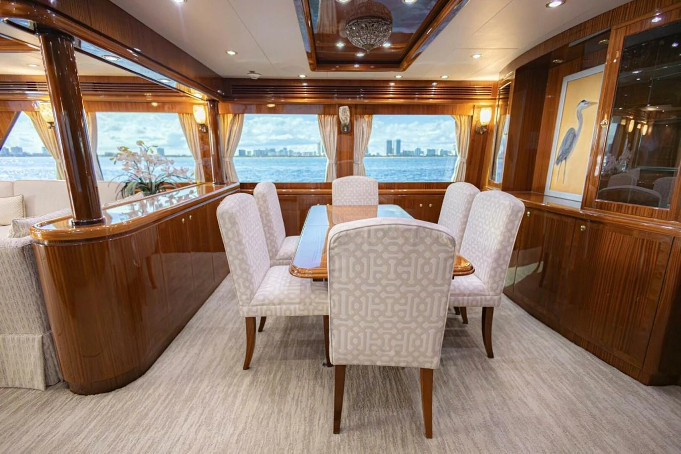 The yacht's dining area features elegant seating with a stunning view of the water through large windows. aboard BOBBI TOO Yacht for Sale