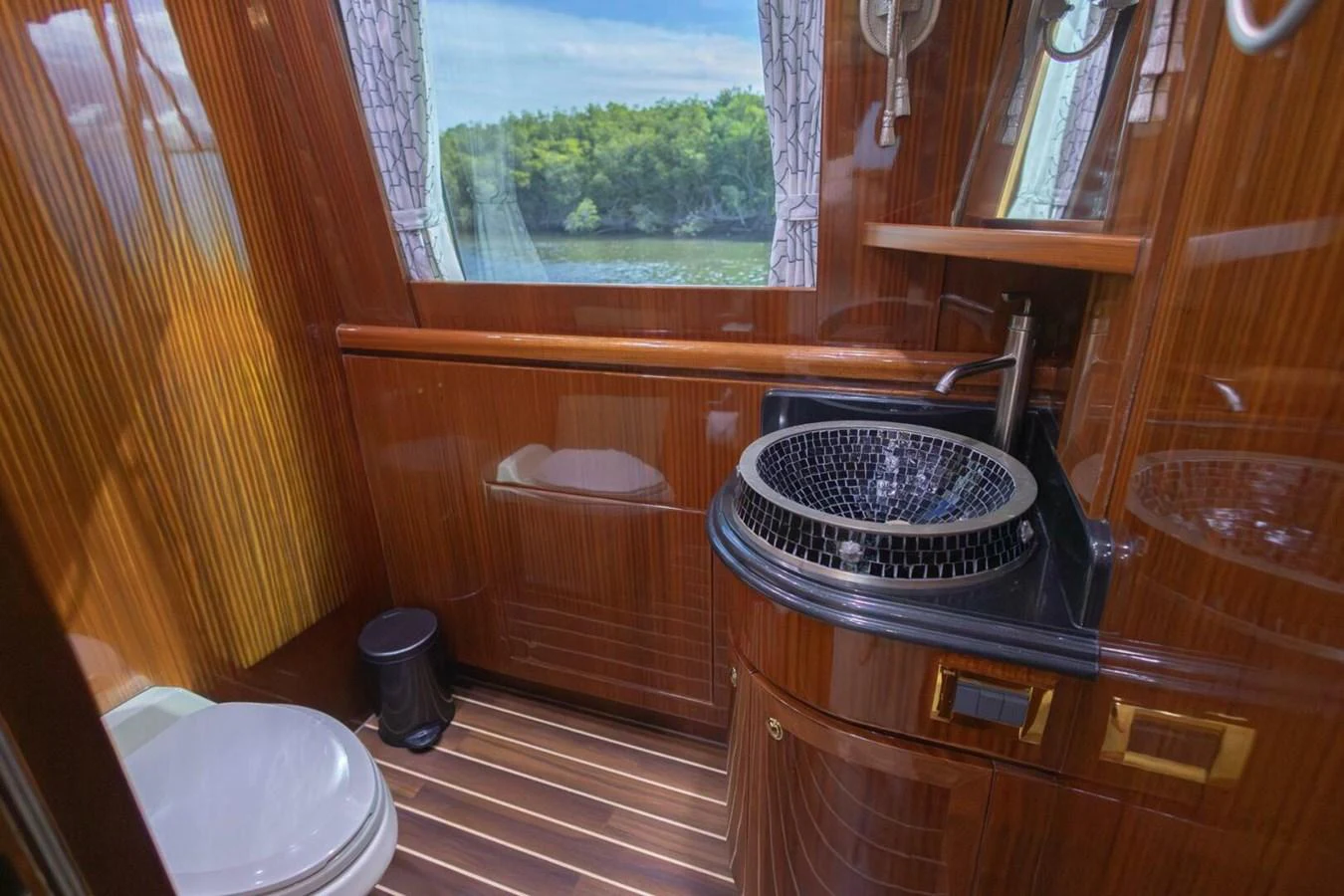 The yacht's bathroom features elegant wood paneling and a stylish sink with a view of the water through the window. aboard BOBBI TOO Yacht for Sale
