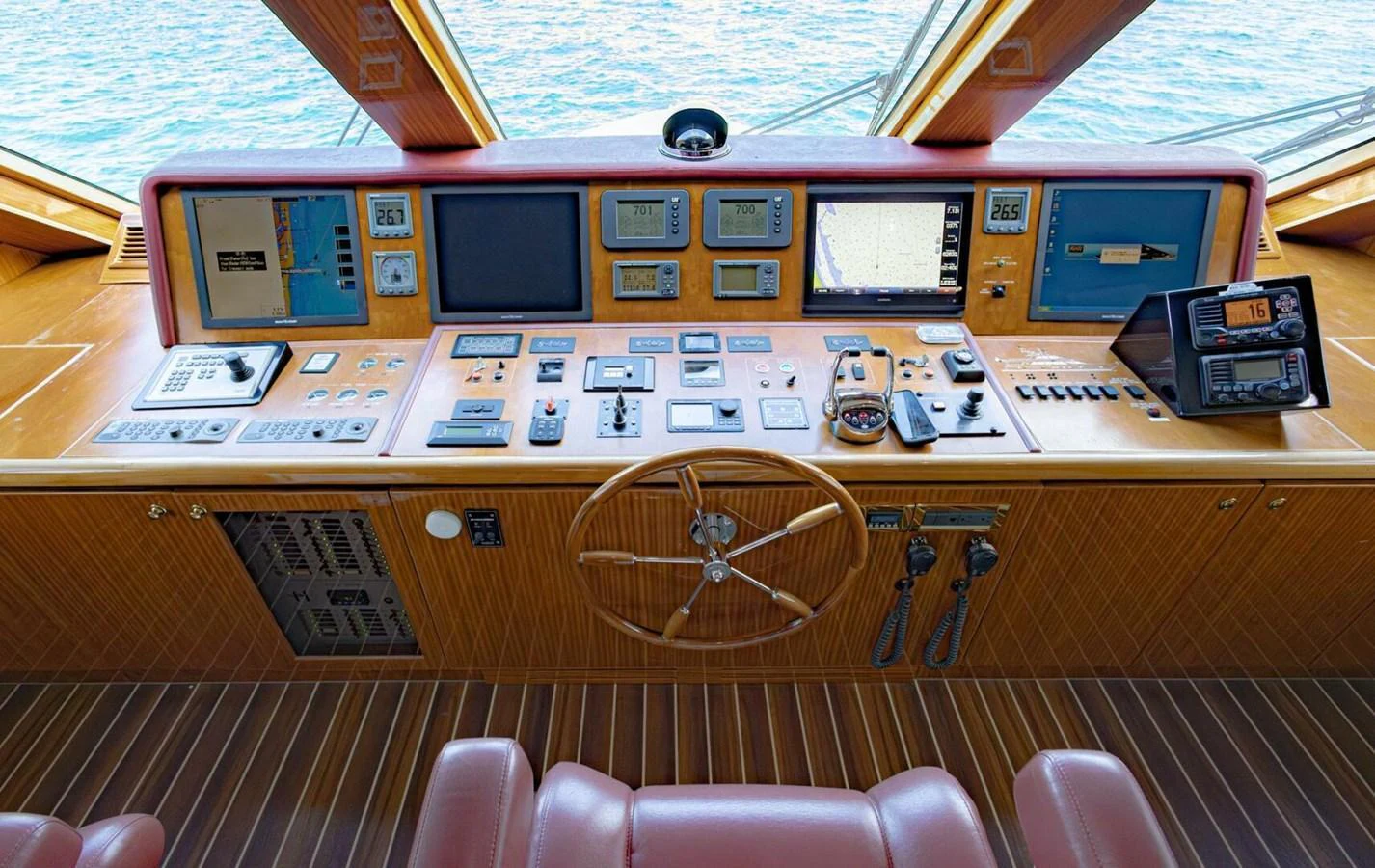 The helm station features a sophisticated array of navigation and control instruments, complemented by a classic wooden steering wheel. aboard BOBBI TOO Yacht for Sale