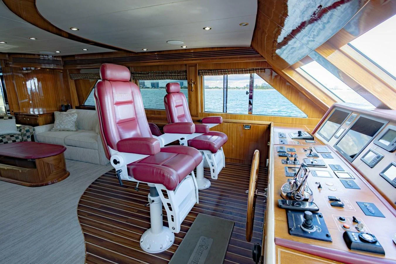 The helm station features luxurious red leather captain's chairs and a comprehensive control panel with a view of the water. aboard BOBBI TOO Yacht for Sale