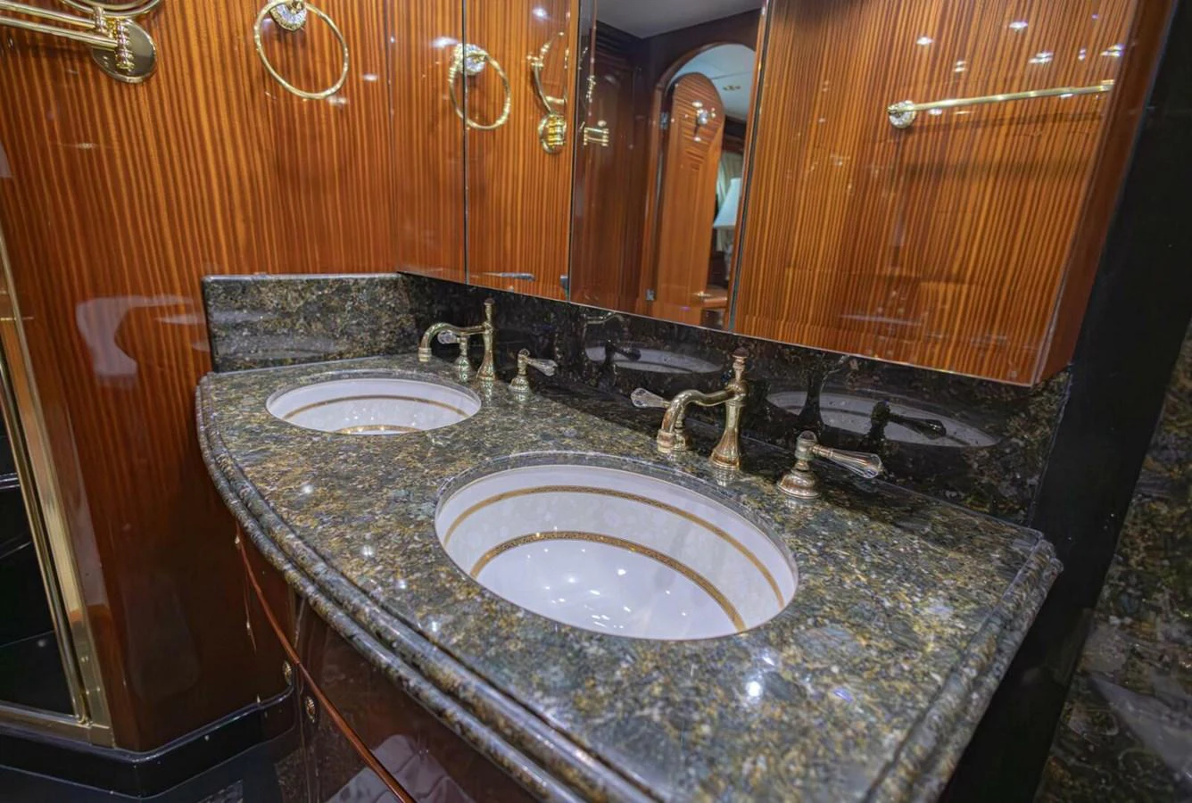 The bathroom features a luxurious double sink vanity with elegant fixtures and rich wood paneling. aboard BOBBI TOO Yacht for Sale
