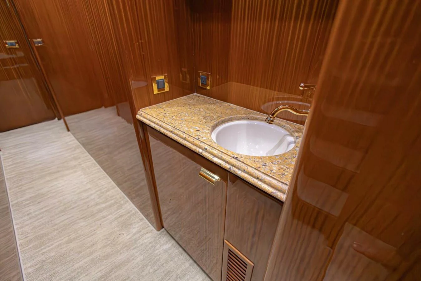 The yacht's bathroom features elegant wood paneling and a polished stone countertop with a sink. aboard BOBBI TOO Yacht for Sale