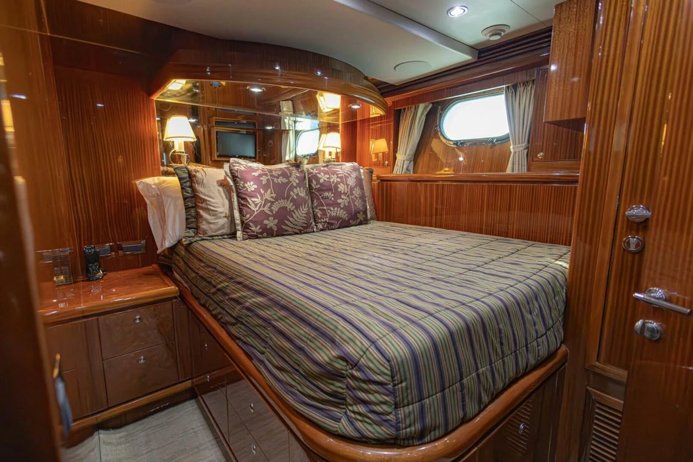 A cozy and elegant stateroom featuring a large bed with striped bedding and wooden cabinetry. aboard BOBBI TOO Yacht for Sale