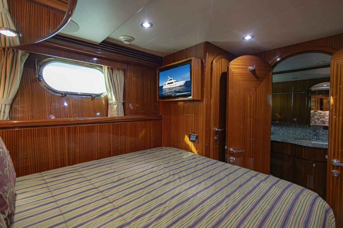 The stateroom features elegant wood paneling, a comfortable bed, and a window for natural light. aboard BOBBI TOO Yacht for Sale