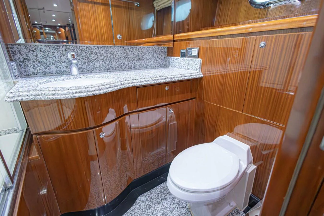 The yacht's bathroom features elegant wood paneling and a sleek granite countertop. aboard BOBBI TOO Yacht for Sale